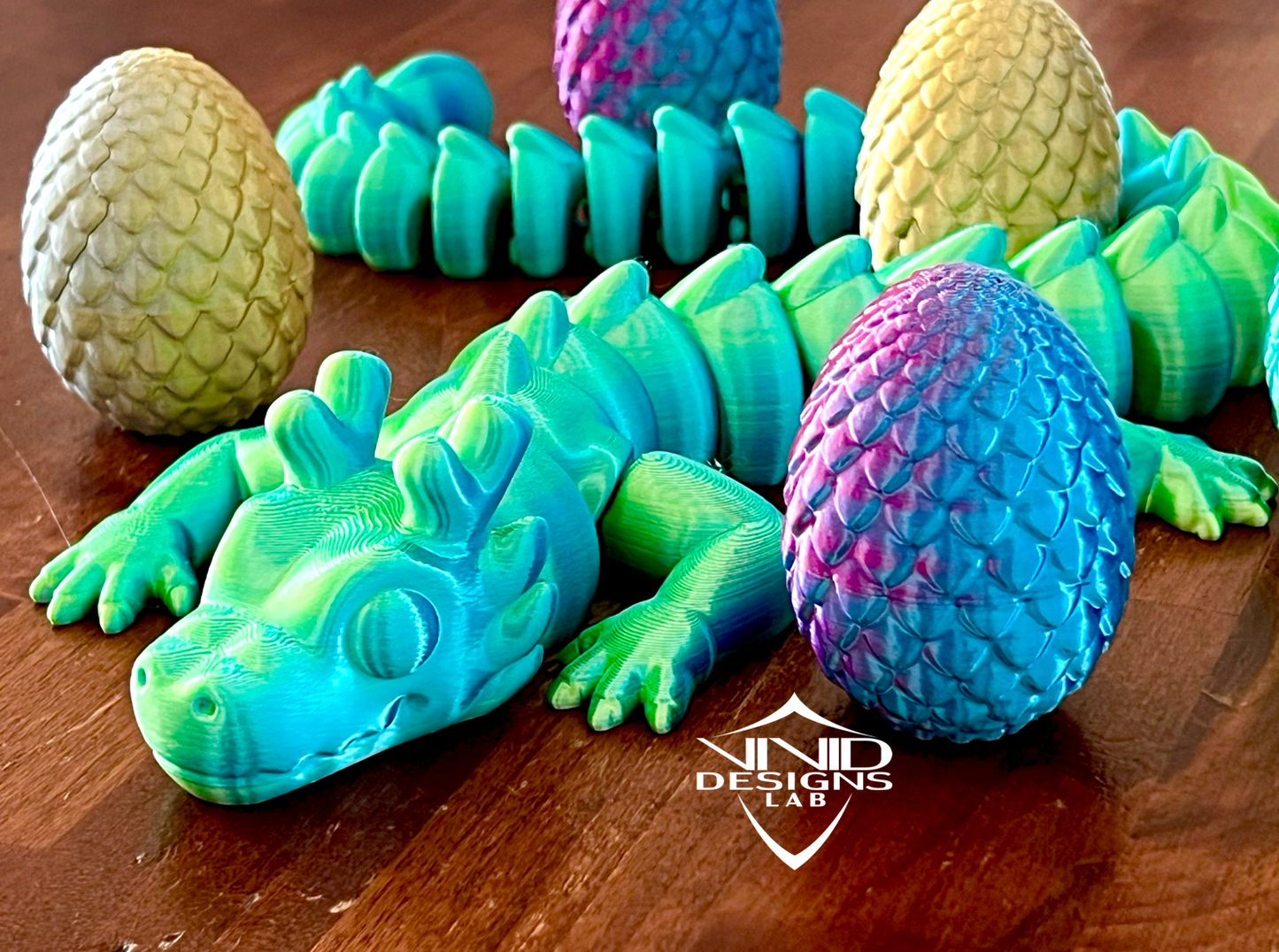 3D printed toy articulated dragon sitting on wood with dragon eggs in the photo, colorful toy