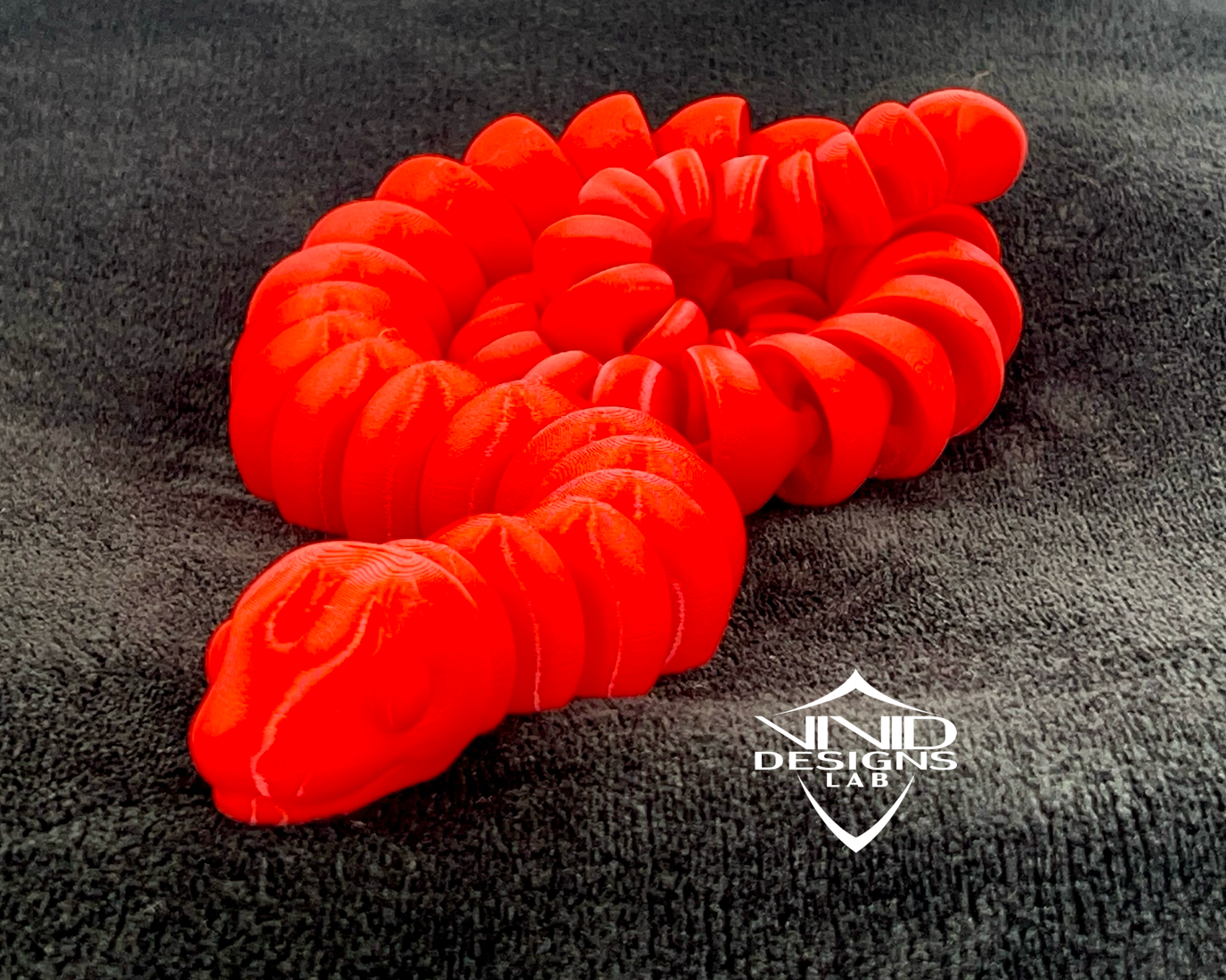 3D printed red snake toy sitting on black fabric