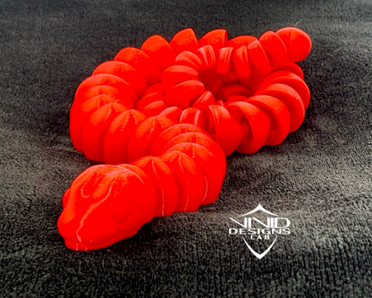 3D printed red snake toy sitting on black fabric